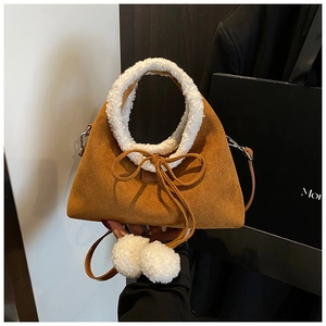 Détail d'un sac en daim marron avec bordure en laine de mouton et pendentifs pompons