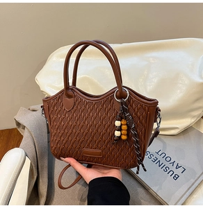 Detail of woven texture on caramel bucket bag with wave edge and tassel accessory