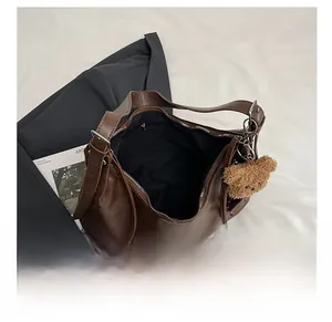 Vue de dessus du grand sac cabas en cuir marron avec poche zippée et breloque ours en peluche