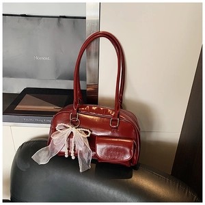 Deep burgundy leather tote bag featuring a decorative lace bow and pearl pendant detail