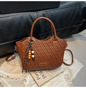 Close-up of brown woven bucket bag featuring adjustable straps and vintage wood beads