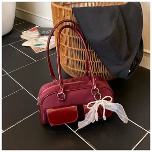Detail of burgundy suede boston bag with patent leather trim and pearl bow charm