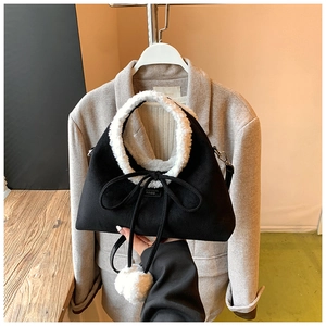 Détail du sac à main noir mat avec bordure en laine d'agneau et accessoire pompon doux