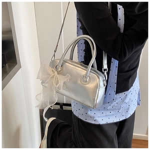 Détail d'un sac à main argenté métallisé avec un nœud en tulle et pendentif perle