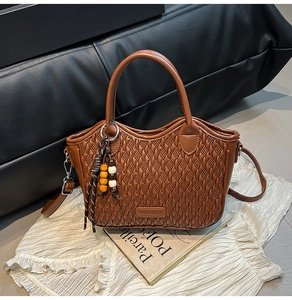 Detail of brown woven texture bucket bag with wooden bead charm and adjustable strap
