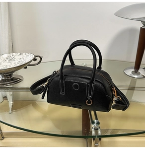Detail of black litchi grain leather bag featuring white contrast stitching and gold hardware