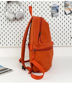 Side view of vibrant orange nylon backpack showing multiple storage layers and compartments
