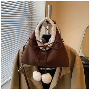 Gros plan d'un sac en daim marron avec bordure en mouton retourné et pompons