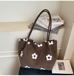 Detail of brown suede tote bag featuring white flower patterns and leather shoulder straps