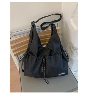 Close-up of black drawstring crossbody bag with textured fabric and fashion woven label