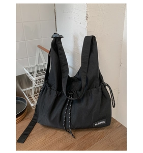 Detail of drawstring closure and fashion label on black nylon large capacity tote bag
