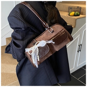 Detail of a brown shoulder bag with velvet texture and pearl bow decoration on the side