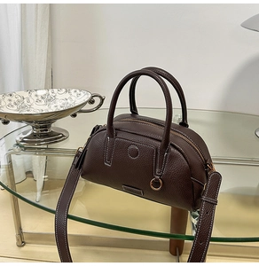 Detail of dark coffee pebble leather handbag with white stitching and metal hardware