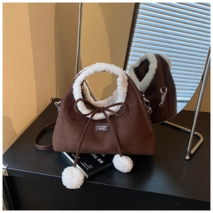 Détail d'un sac à main en daim marron avec bordure en peau lainée blanche et nœud élégant