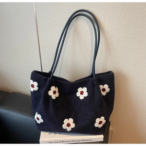 Detail of navy tweed tote bag featuring white floral embroidery and faux leather straps