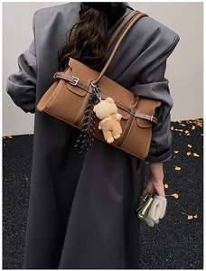 Détail d'un sac Boston marron en daim avec boucles métalliques et pendentif ours