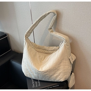 Detail der cremeweißen gesteppten Hobo-Tasche mit passendem Beutel auf Sofa