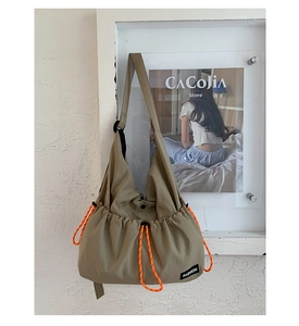 Detail of olive green nylon bag showing orange drawstrings and Fashion label