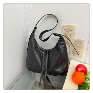 Détail d'un sac hobo noir avec fermeture éclair argentée et longue tirette en cuir