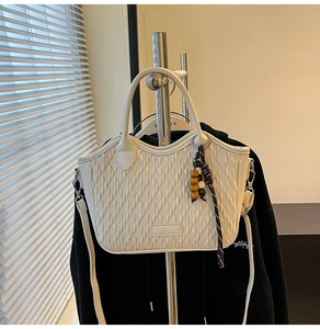 Detail of beige bucket bag featuring woven quilted texture and wooden bead charm accessory
