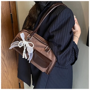 Detail of brown suede tote bag with shiny leather pockets and white organza bow decoration