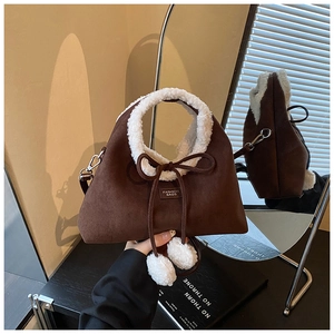Détail du sac à main en daim marron avec bordure en fausse fourrure blanche et pompons
