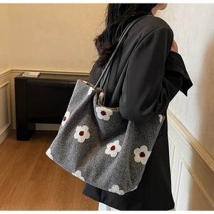 Macro view of grey textured wool tote bag featuring white floral patterns and long shoulder straps