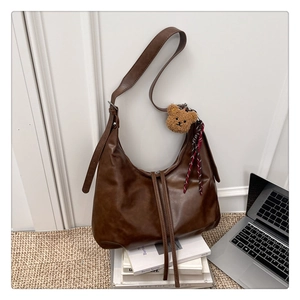 Détail du sac croissant en similicuir marron avec bandoulière et pendentif ours