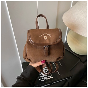 Close-up of brown suede mini backpack with flower embroidery and small brand lettering