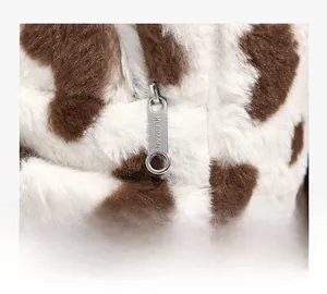 Detail view of silver metal zipper with brand engraving on plush cow print backpack