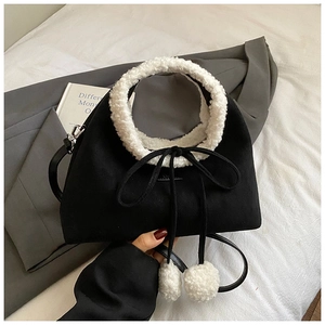 Détail du sac mat noir avec bordure en laine d'agneau blanche et pompons en peluche