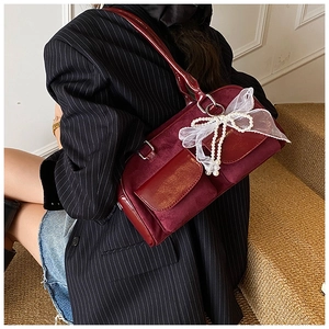 Detail of red velvet shoulder bag with lace bow, pearl chain and glossy flip pockets
