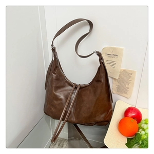 Vue détaillée de la texture du sac hobo en cuir marron foncé et de sa fermeture
