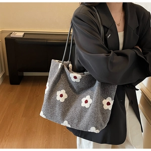 Detail of grey felt tote bag featuring white floral embroidery and slim black shoulder straps