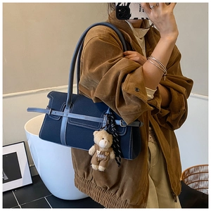 Détail du sac Boston en toile bleu marine avec garniture en cuir et breloque ours