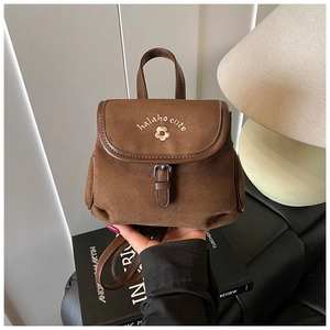 Detail of vintage brown suede backpack with floral embroidery and leather trim