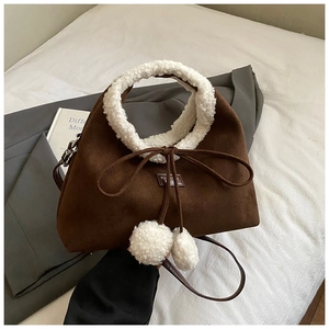 Détail du sac à bandoulière en daim avec bordure en peau lainée et nœud à pompons