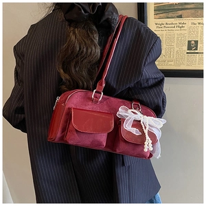Close-up of burgundy velvet underarm bag with white lace bow and pearl charm
