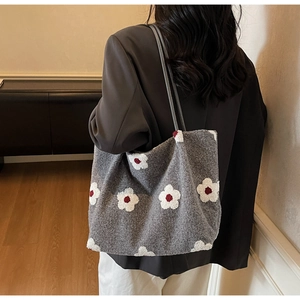 Detail of grey plush tote bag with white flower pattern shown on model's shoulder