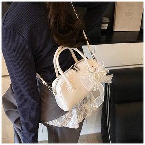 Gros plan sur un sac en cuir blanc avec un grand nœud en organza et des perles décoratives