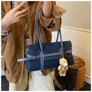 Détail du sac Boston avec bordures bleues contrastées et un pendentif ours en peluche