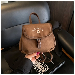 Detailed embroidery of white flowers and text on the coffee-colored suede mini backpack