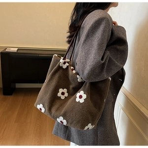 Detail of deep brown wool tote bag featuring white floral embroidery and long handles