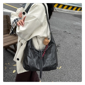 Détail du grand sac hobo noir avec un pendentif ours mignon et un ruban à carreaux