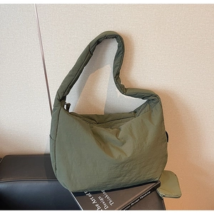 Detail der armeegrünen gesteppten Umhängetasche mit passender Geldbörse auf einem Sofa