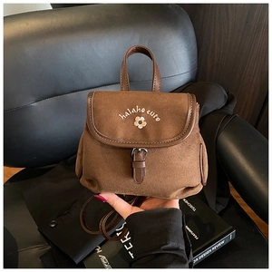 Close-up of retro brown frosted backpack featuring delicate floral embroidery and leather strap