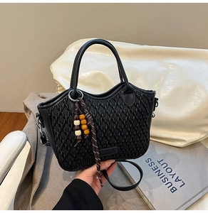 Detail of black woven bucket bag with beaded tassel and adjustable crossbody strap