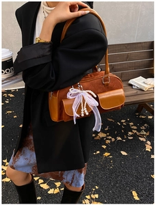 Brown vintage tote bag with dual pockets and pearl bow charm shown in outdoor setting