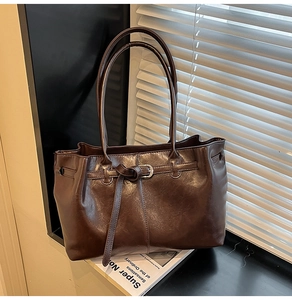 Détail du sac fourre-tout vintage marron foncé avec boucle et fines bretelles sur fenêtre