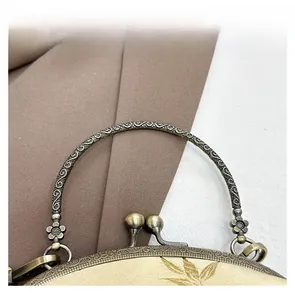 Detail of vintage champagne silk shell bag with bronze floral handle and embroidery